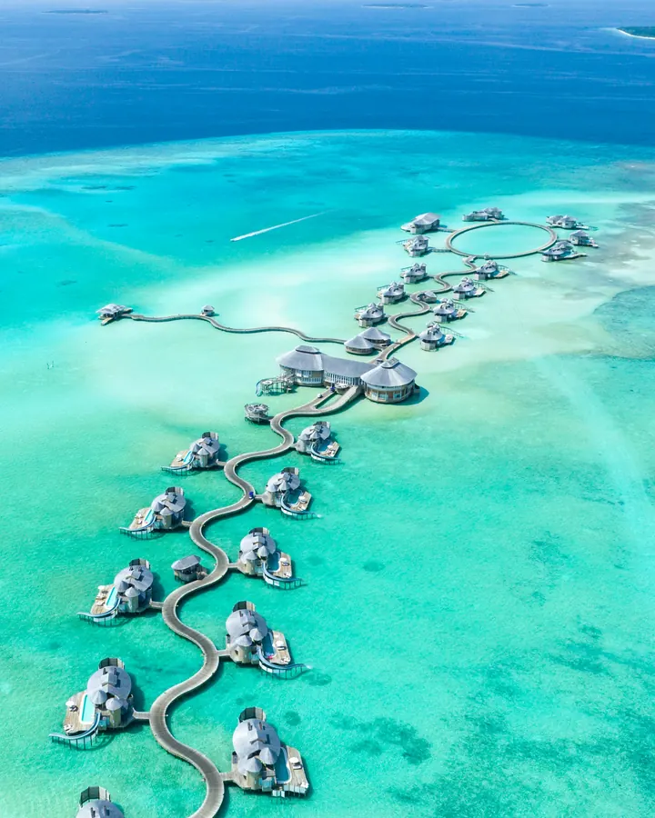 Overwater villas above a clear turquoise lagoon in the Maldives